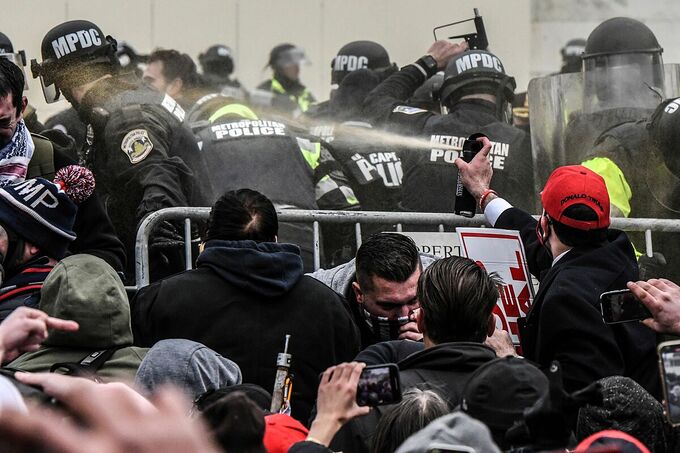 Người biểu tình xịt hơi cay vào cảnh sát bảo vệ ngoài Đồi Capitol hôm 6/1. Ảnh: Reuters.
